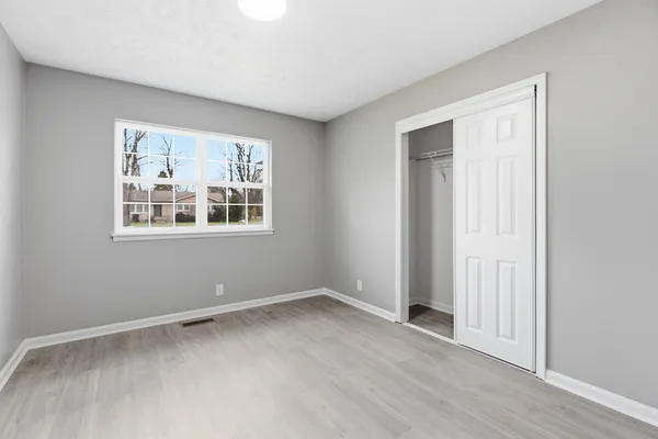 an empty room with wooden floor and windows