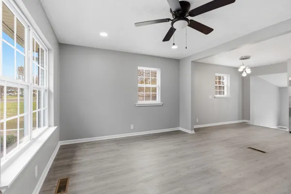 a view of an empty room with a window and wooden floor