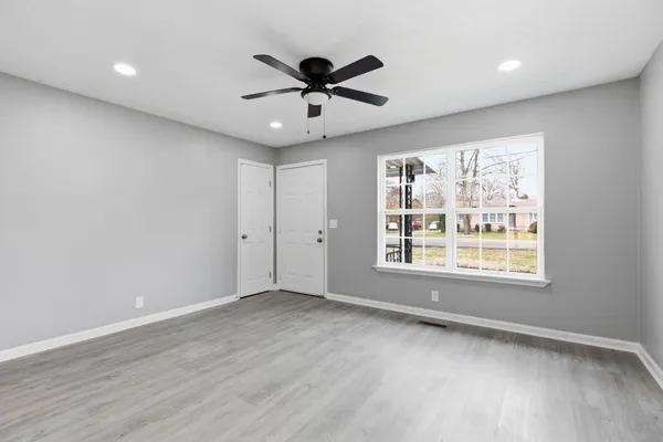 a view of an empty room with a window and wooden floor