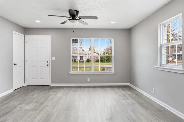 an empty room with wooden floor and windows