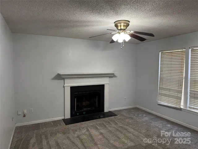 a view of an empty room with window and chandelier fan