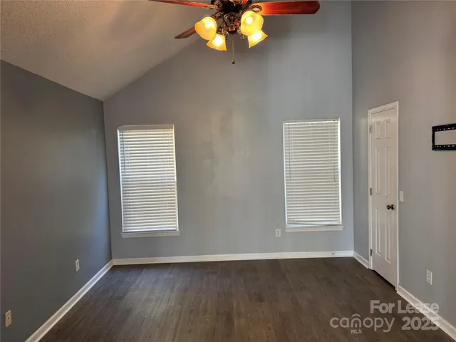 an empty room with wooden floor cabinet and windows