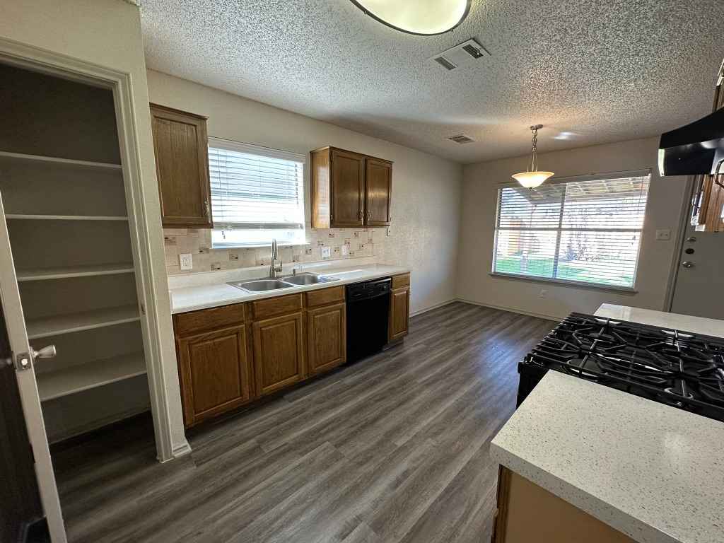 814 Smoke Signal Pass Pflugerville, TX 78660 - Photo 11 of 29 Kitchen featuring light countertops, hanging light fixtures, dark wood-style floors, black appliances