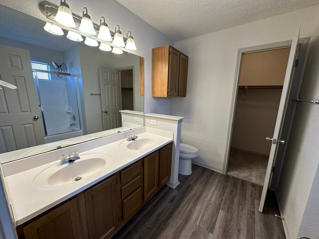 814 Smoke Signal Pass Pflugerville, TX 78660 - Photo 19 of 29 Master Full bath featuring a textured ceiling, double vanity, bathtub / shower combination, dark wood-style flooring, and a spacious closet