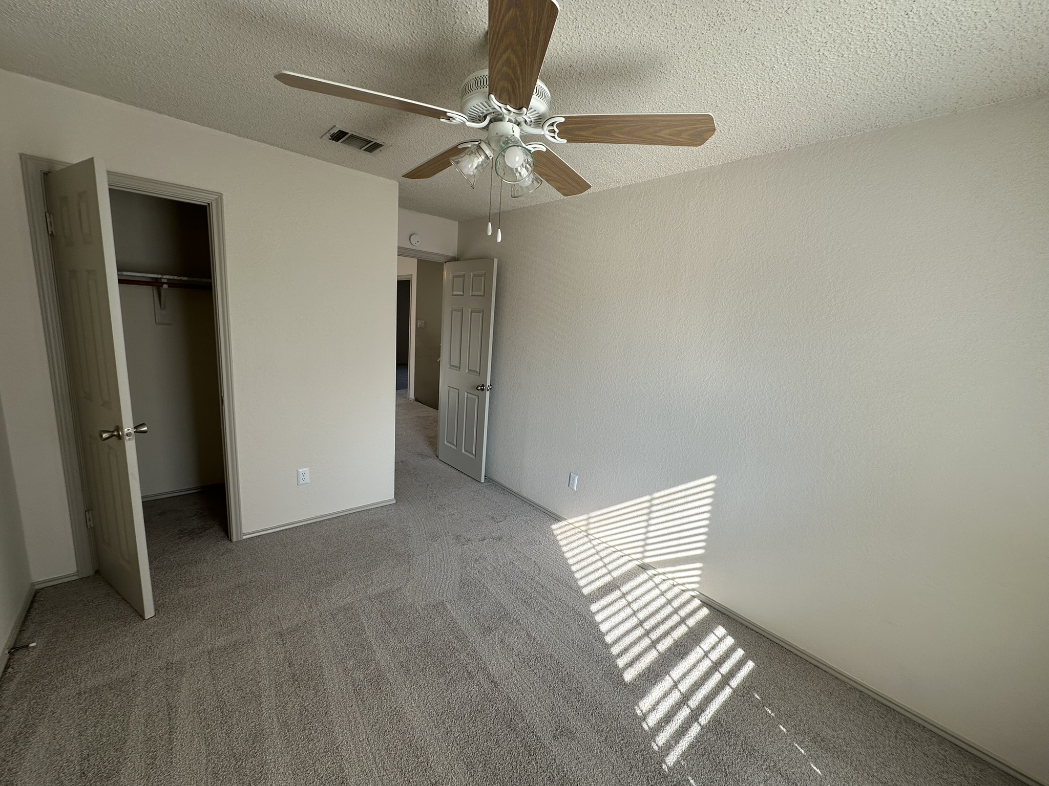 814 Smoke Signal Pass Pflugerville, TX 78660 - Photo 25 of 29 Unfurnished bedroom with carpet flooring, a spacious closet, a textured ceiling, and a ceiling fan