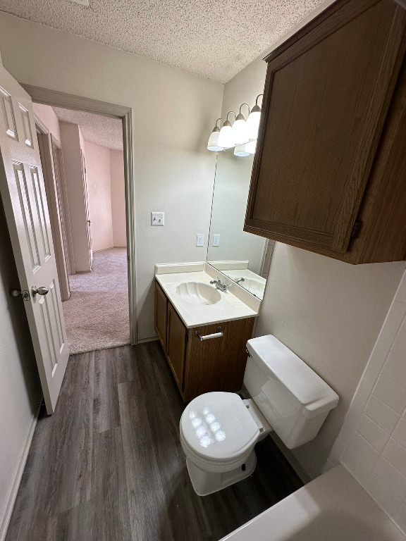 814 Smoke Signal Pass Pflugerville, TX 78660 - Photo 29 of 29 Bathroom featuring vanity, a textured ceiling, dark wood finished floors, and a tub to relax in