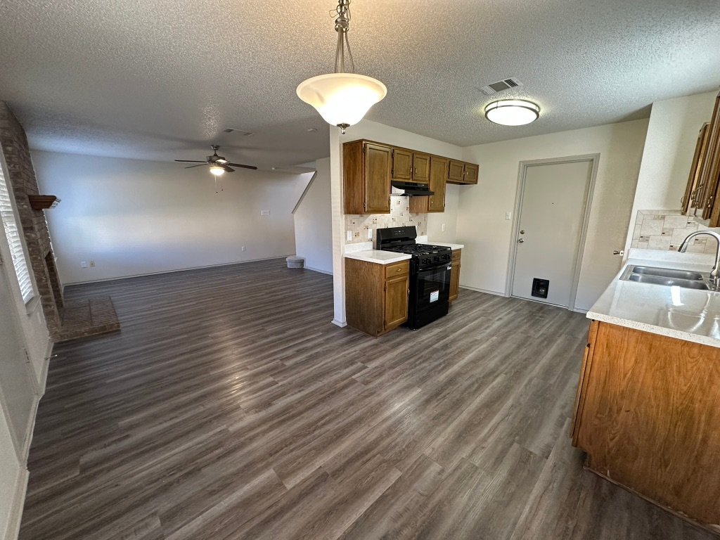 814 Smoke Signal Pass Pflugerville, TX 78660 - Photo 8 of 29 Kitchen featuring black range with gas stovetop, a pendant lighting, brown cabinetry, and a ceiling fan
