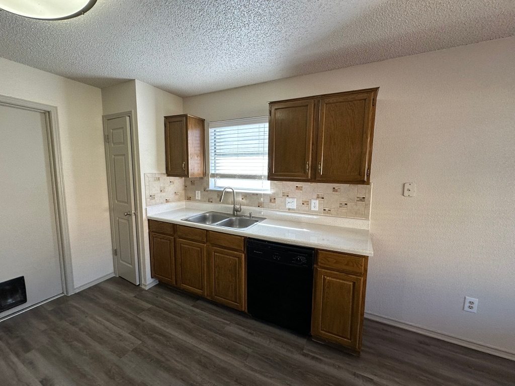 814 Smoke Signal Pass Pflugerville, TX 78660 - Photo 10 of 29 Kitchen with light countertops, black dishwasher, dark wood-style flooring, and dark brown cabinets