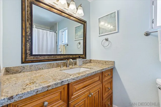 a bathroom with a granite countertop sink and a mirror