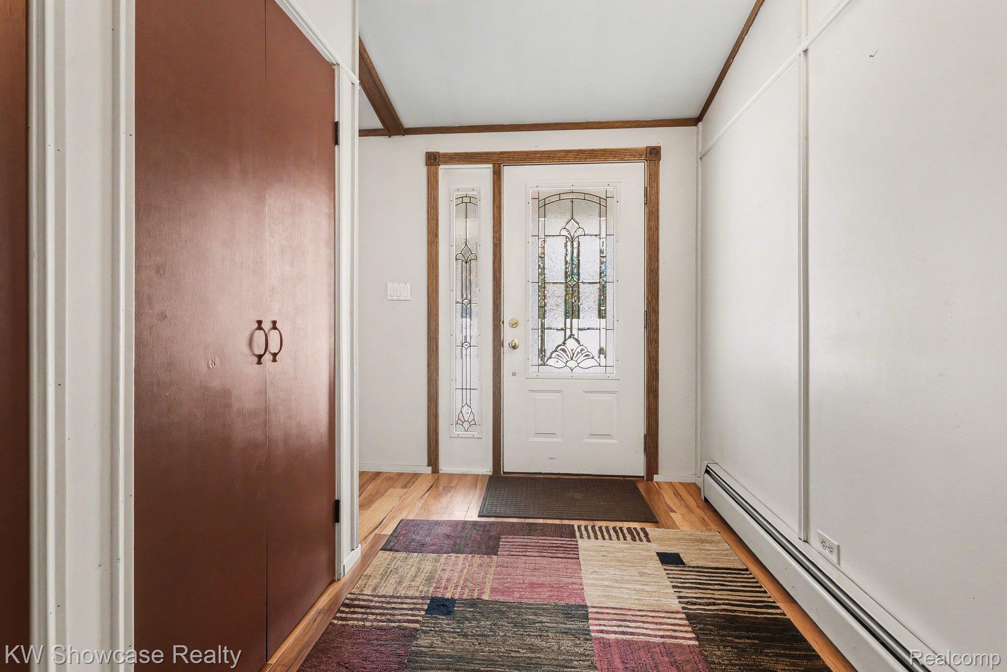 1951 East Kneeland Road Fairview, MI 48621 - Photo 4 of 46 Entrance foyer featuring baseboard heating, light wood-style flooring, and crown molding