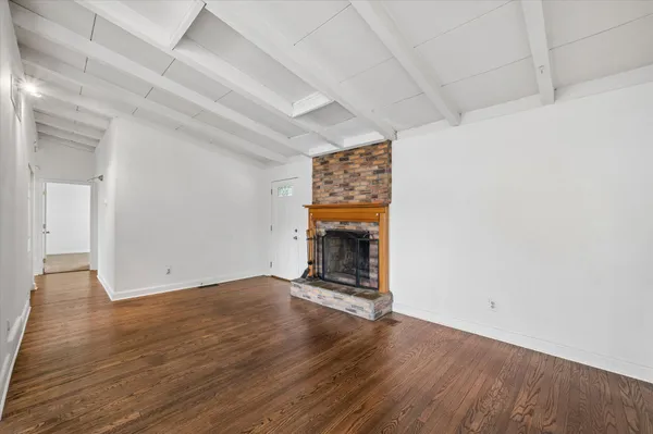 an empty room with wooden floor fireplace and windows