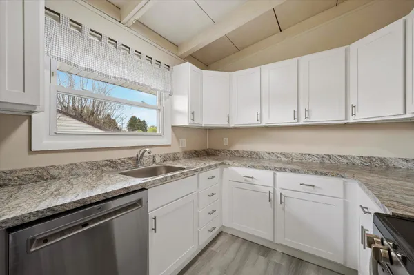a kitchen with granite countertop stainless steel appliances white cabinets granite counter tops and a wooden floors