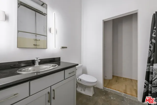 a bathroom with a granite countertop sink a toilet and a mirror