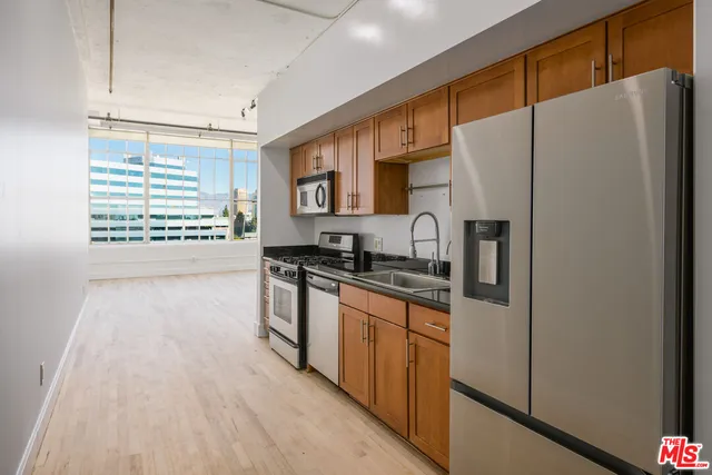 a kitchen with stainless steel appliances a refrigerator a sink and white cabinets