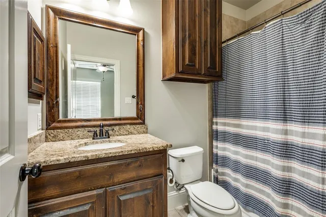 a bathroom with a granite countertop toilet sink and mirror