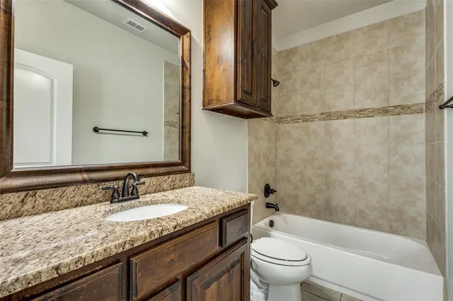 a bathroom with a granite countertop sink a toilet and shower