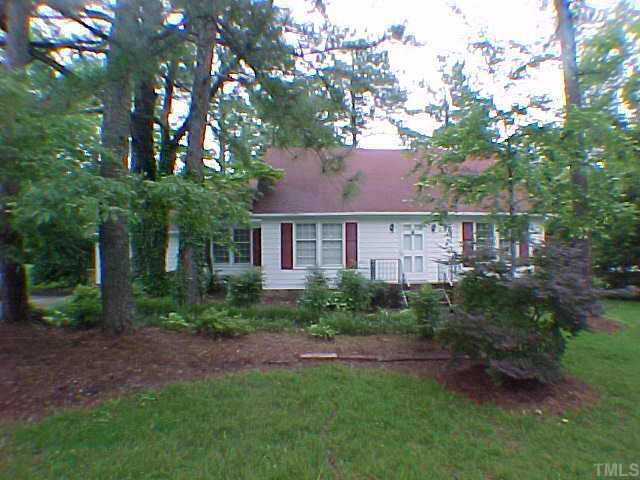 a view of a yard in front of a house with plants and large tree