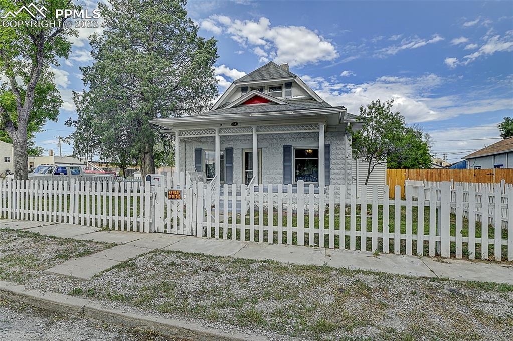 a white house that has a small yard and large trees