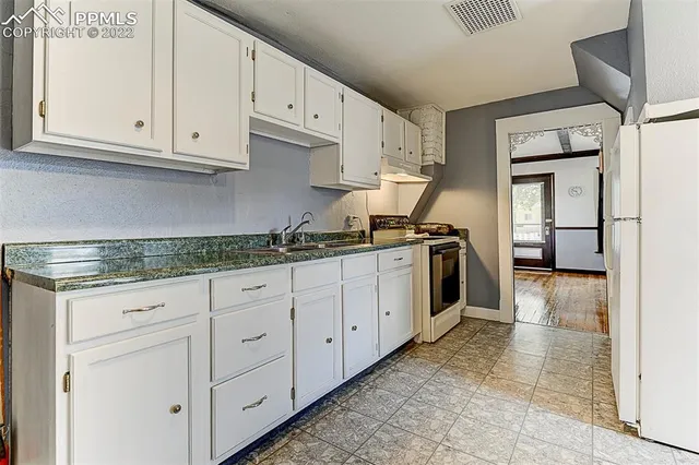 a kitchen with granite countertop white cabinets and stainless steel appliances