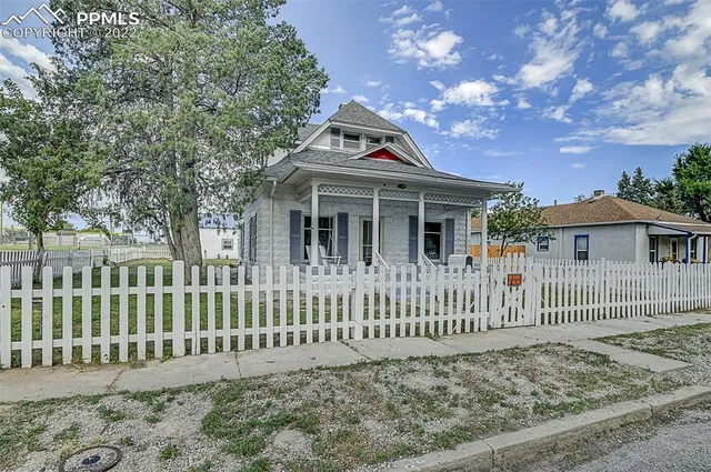 a view of a house with a small yard and wooden fence