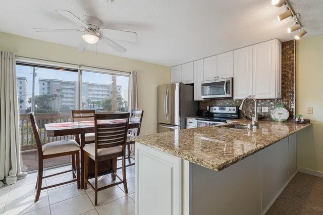a kitchen with stainless steel appliances granite countertop a stove top oven a sink a dining table and chairs