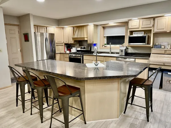 a kitchen with granite countertop a table chairs microwave and refrigerator