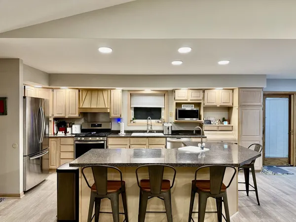 a kitchen with microwave a refrigerator and chairs