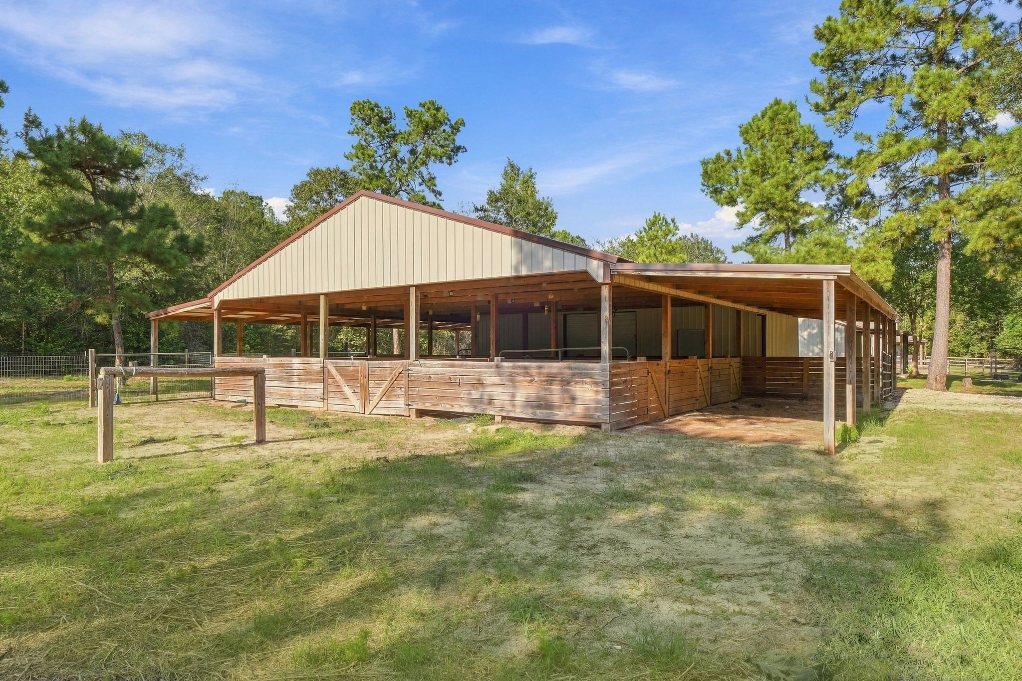 7049 Pine Shadows Road Cleveland, TX 77328 - Photo 40 of 49 A spacious and well-maintained horse stable set amidst lush greenery, offering ample shelter and storage for equestrian needs.