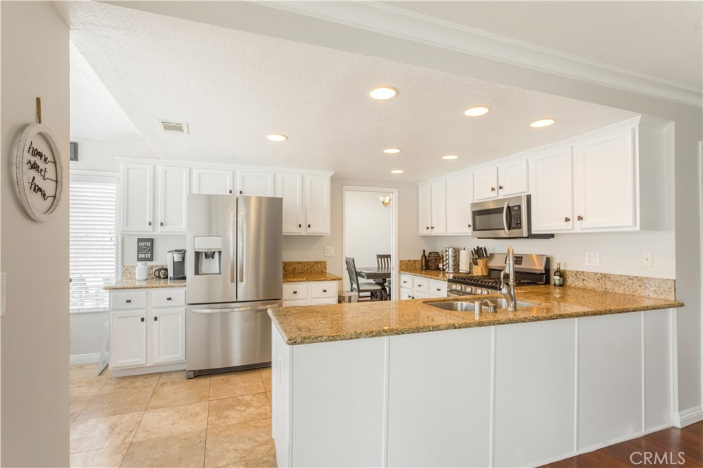 934 Mission Grove Riverside, CA 92506 - Photo 12 of 28 a kitchen with stainless steel appliances granite countertop a refrigerator sink stove and white cabinets