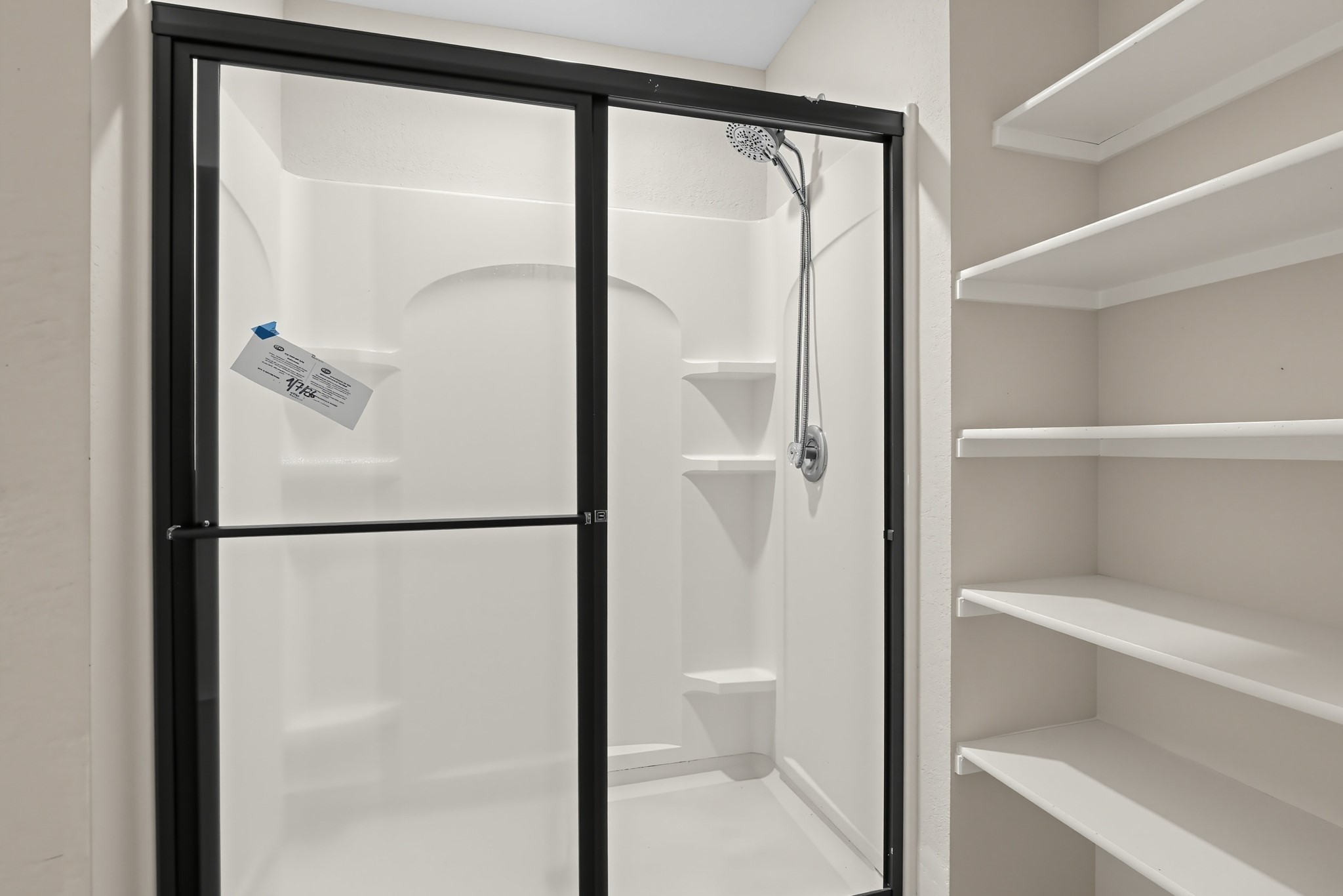 11810 Pyrite Road Manor, TX 78653 - Photo 13 of 38 A modern walk-in shower sits adjacent to built-in shelving.
