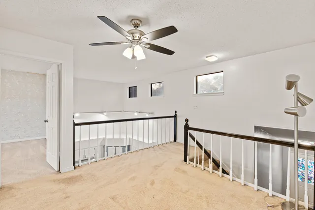 an empty room with windows and fan