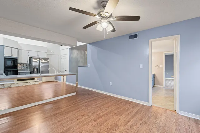 a view of an empty room with wooden floor and a window