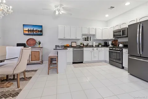 a kitchen with stainless steel appliances a stove a sink a dining table and chairs