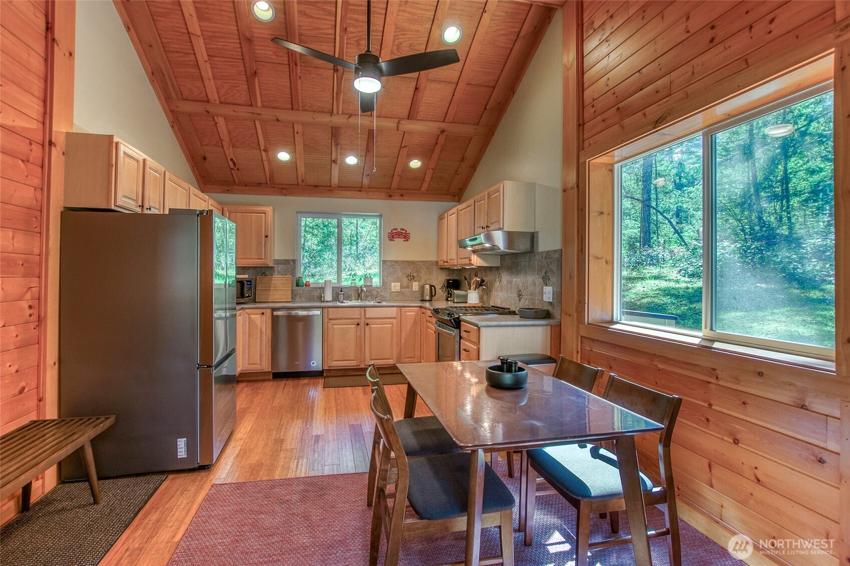 744 Tarte Road Friday Harbor, WA 98250 - Photo 9 of 35 a kitchen with stainless steel appliances granite countertop a refrigerator a sink dishwasher a stove and a dining table with wooden floor