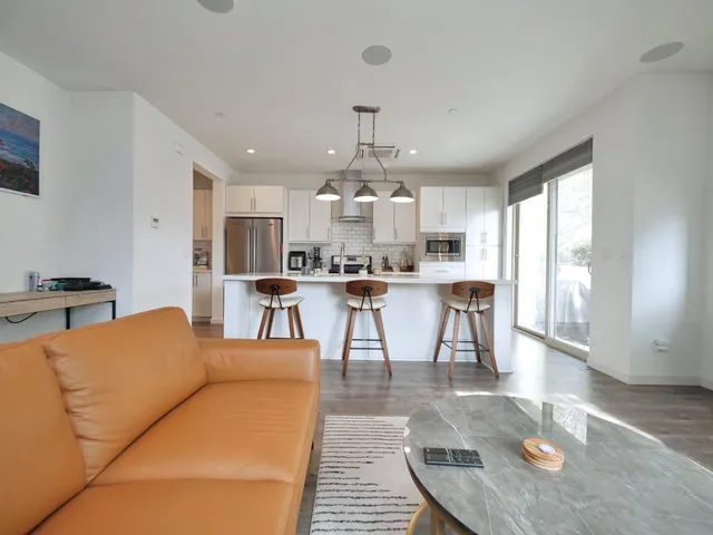 a living room filled with furniture and kitchen view