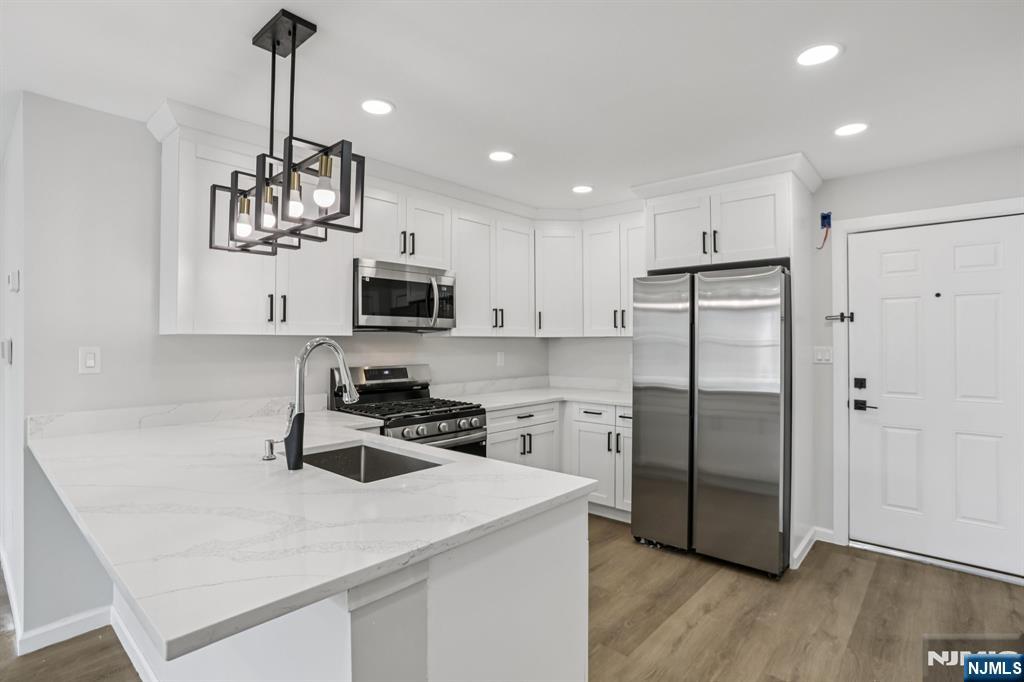 a kitchen with stainless steel appliances a sink a stove a refrigerator and cabinets