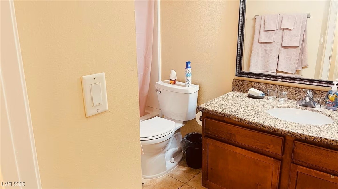 7300 West Pirates Cove Road, Unit 1039 Las Vegas, NV 89145 - Photo 29 of 30 Bathroom featuring vanity, shower / bath combo with shower curtain, a textured wall, and light tile patterned flooring
