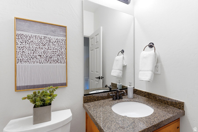 1712 Somerset Ridge Drive Draper, UT 84020 - Photo 31 of 76 Powder room featuring a granite countertop, undermount sink, bronze-finish faucet, framed mirror, and light wood-finish cabinetry
