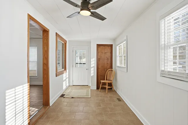 a view of a hallway with a chandelier fan and windows