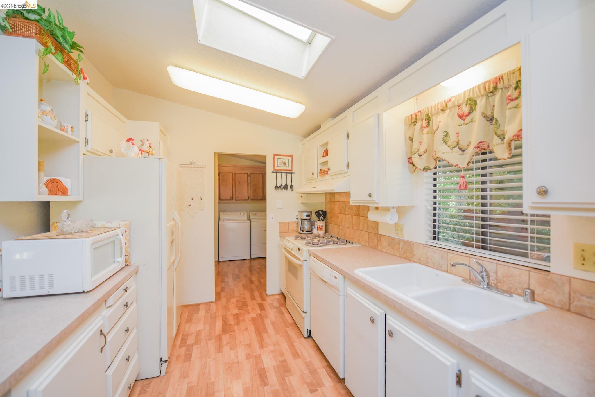 18717 Mill Villa Road, Unit 235 Jamestown, CA 95327 - Photo 10 of 26 Kitchen featuring independent washer and dryer, white appliances, white cabinetry, and vaulted ceiling