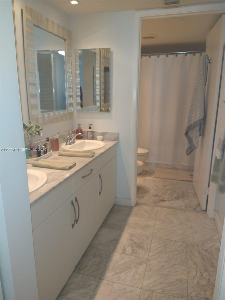 9341 Collins Avenue, Unit 806 Surfside, FL 33154 - Photo 14 of 27 a bathroom with a double vanity sink toilet and shower