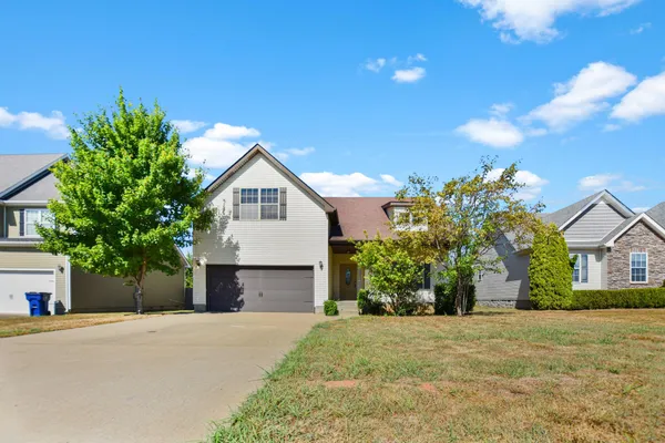 a front view of house with yard and trees in the background