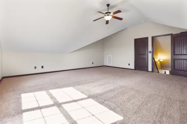 an empty room with windows and chandelier fan