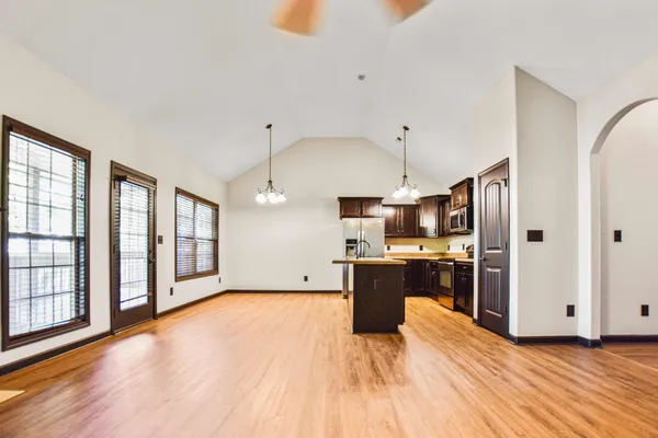 a large kitchen with stainless steel appliances granite countertop a refrigerator oven a sink dishwasher and white cabinets with wooden floor