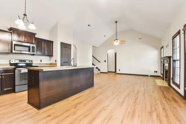 a kitchen with stainless steel appliances granite countertop a stove a refrigerator a sink dishwasher and a oven with wooden floor