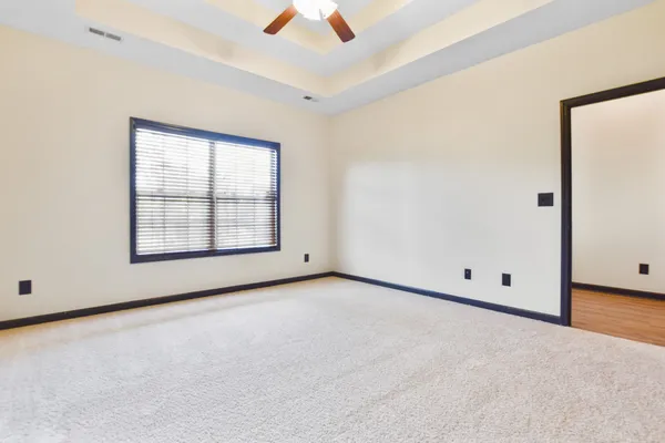 an empty room with ceiling fan and windows