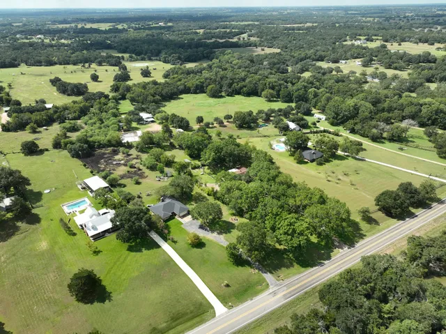 an aerial view of a residential houses with outdoor space and trees