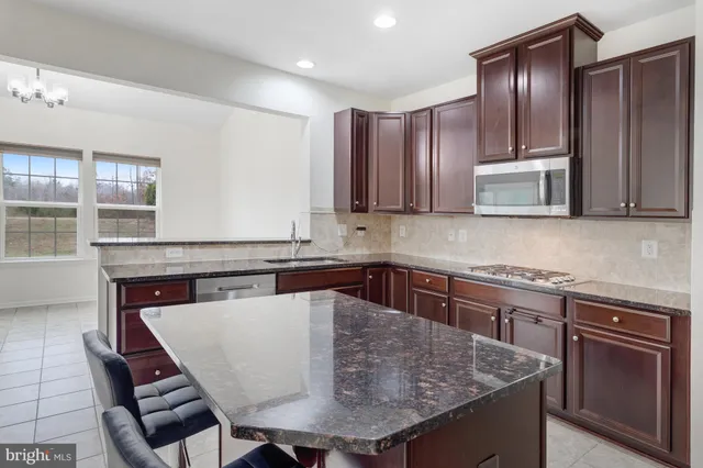 a kitchen with stainless steel appliances granite countertop a kitchen island a stove a sink a microwave and dining table