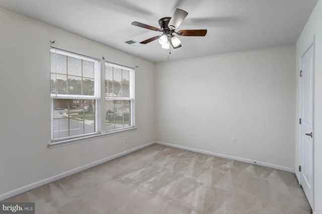 an empty room with window and ceiling fan