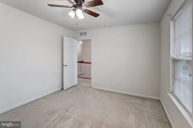 an empty room with chandelier fan and windows
